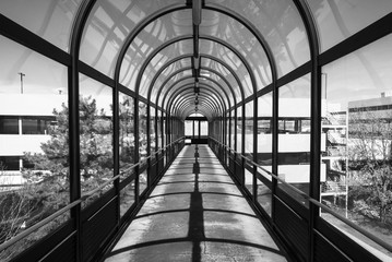Abstract industrial outdoor covered walkway glass tunnel. Pedestrian bridge walkway tunnel. Glass and steel design and detail. 