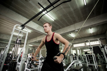 Fototapeta na wymiar Man workout on exercise machine in gym. Pretty young man training in the gym