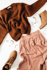 Fashion look composition with brown sweater, shoes, skirt on white background. Flat lay, top view.