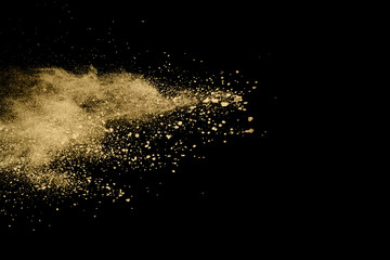 Golden powder explosion on black background. Freeze motion.