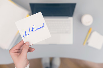 Woman clerk sitting holding note paper sticker with Welcome word. Business concept. Concept.