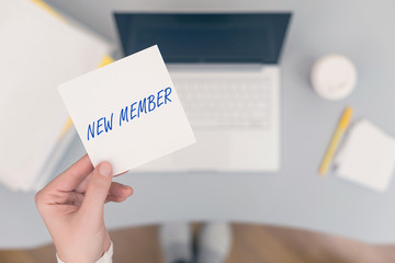 Woman clerk sitting holding note paper sticker with new member phrase. Business concept. Concept.