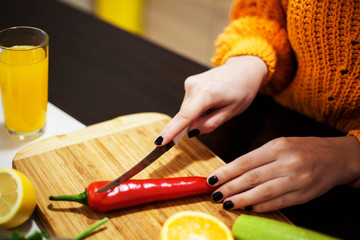 Midsection of woman chopping red bell pepper in kitchen .