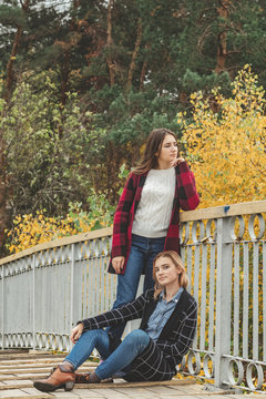 Two cute beautiful young women on the wooden bridge
