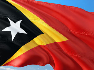Flag of East Timor waving in the wind against deep blue sky. High quality fabric.
