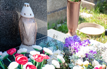 White cemetery candle burning  on the grave in sunny day
