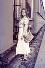 A girl stands on the steps of the cars train. Historical monochrome photo of a woman on the footboard of the car. The vintage train is at the station