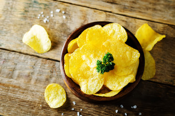 Potato chips with salt on a wood background