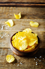 Potato chips with salt on a wood background