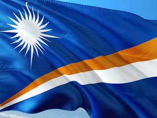 Flag of Marshall Islands waving in the wind against deep blue sky. High quality fabric.