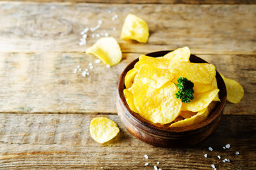 Potato chips with salt on a wood background