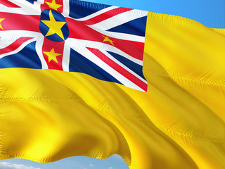Flag of Niue waving in the wind against deep blue sky. High quality fabric.