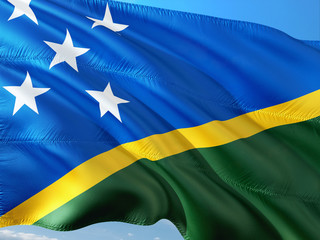 Flag of Solomon Islands waving in the wind against deep blue sky. High quality fabric.