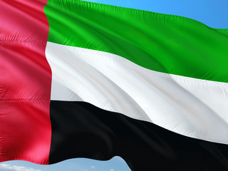 Flag of United Arab Emirates waving in the wind against deep blue sky. High quality fabric.