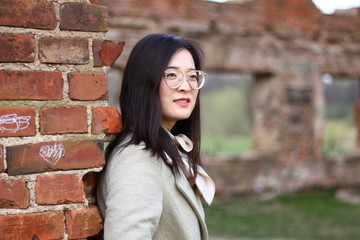 Beautiful Asian girl in glasses at the ancient ruined building background