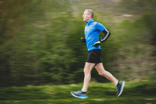 Senior Man in 50s Running with motion panning blurred background