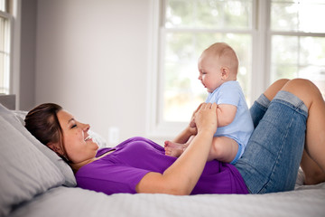 Mother Holding Baby Boy on Bed in Bedroom