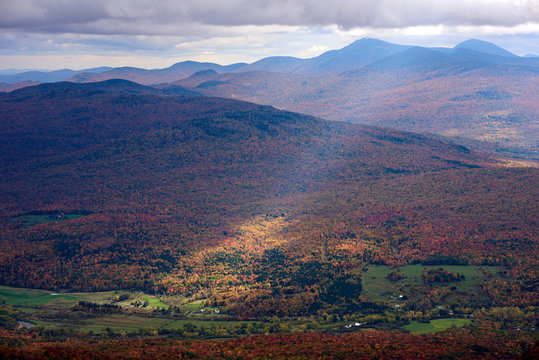 A Sunbeam Shines Through The Clouds To The Autumn Coloured Forest Below; Dunham, Quebec, Canada