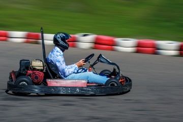 Man behind the wheel of a kart. Karting on racing round in the open air. Man rides on a kart with high speed.