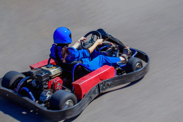 Karting on racing round in the open air. Woman behind the wheel of a kart. Girl rides on a kart...