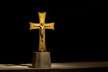 Gold crucifix dramatically illuminated with black background; Florence, Tuscany, Italy