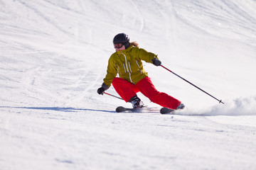 Young woman downhill skiing on an open slope at a ski resort in the Canadian Rocky Mountains,...