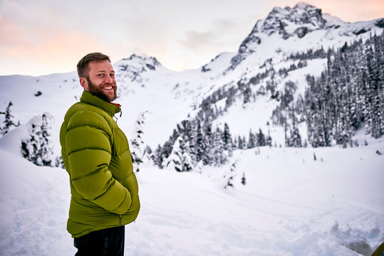 Portrait of a man standing in the snow-covered mountains at dusk; British Columbia, Canada