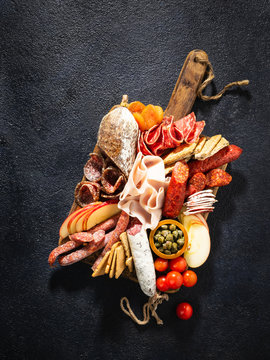 Assortment of salami and snacks. Sausage Fouet, sausages, salami, paperoni. On a black wooden background. Top view. Free space for your text