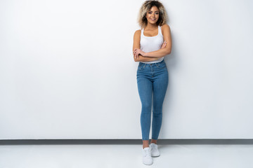 Full length portrait of stylish young black woman standing on white background.