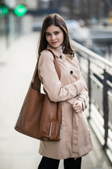 Young woman walking on the street wearing stylish bright coat with handsbag