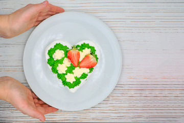 Green meringue cake with strawberries. French dessert with whipped cream. Delicious cake covered with green cream. The cake hands served to the table