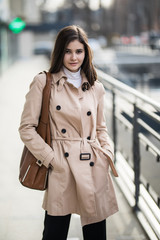 Beautiful brunette young woman in nice coat and sunglasses on urban background.