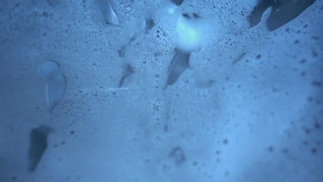 Foam flows down the glass with splash in super slow motion.