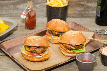 Homemade delicious three mini burgers served with salad, sauce and french fries. Homemade mini burger sliders. 