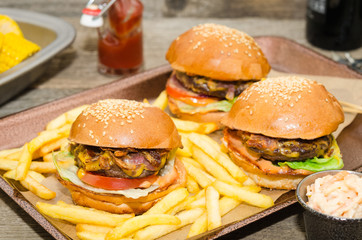 Homemade delicious three mini burgers served with salad, sauce and french fries. Homemade mini burger sliders. 