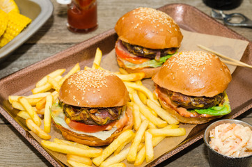 Homemade delicious three mini burgers served with salad, sauce and french fries. Homemade mini...