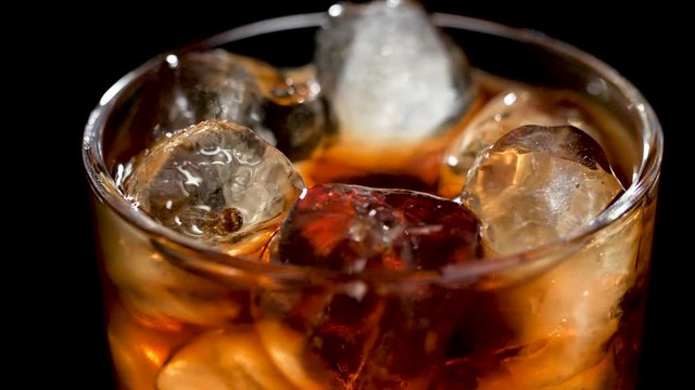 Ice tea or cocktail glass, spinning over a black background.