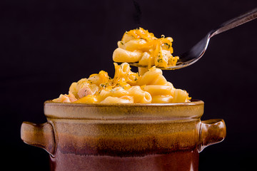 Mac and cheese on a fork over the bowl.
