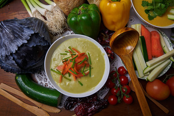 Aerial still life. Cream of asparagus and peas. Craft bread, tomatoes, peppers, garlic, zucchini, carrots, dried peppers, cilantro, red cabbage, pumpkin. 