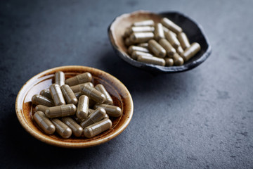 Gotu Kola (Centella Asiatica) capsules. Concept for a healthy dietary supplementation. Dark stone background. Close up. Copy space. 