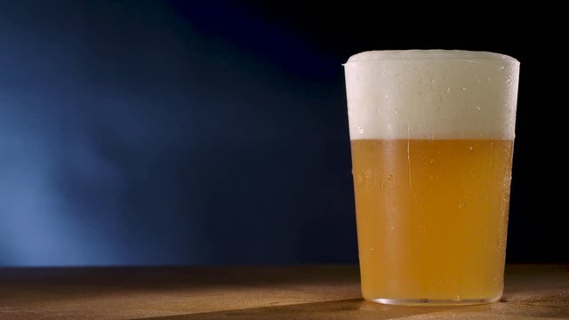 Cold unfiltered beer glass with water drops.