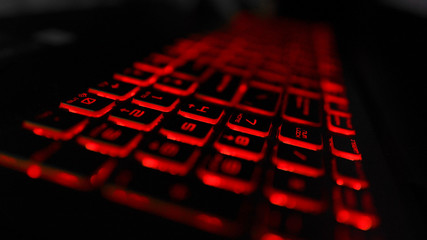 Close up of laptop gaming keyboard illumination technology, red backlit keyboard