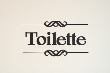 Scritta toilette fotografata sulla porta di un bagno pubblico.