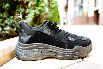 black sneakers on thick black soles against the background of paving slabs
