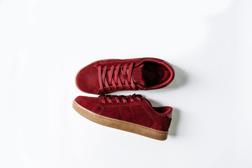 fashionable burgundy suede sneakers on a beige sole and on a white background