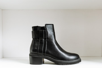 black leather shoe with low heels on a white shelf in the store