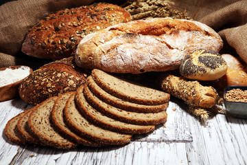 Assortment of baked bread and bread rolls on rustic white bakery table background