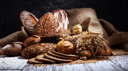 Assortment of baked bread and bread rolls on rustic white bakery table background