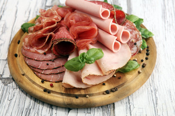 Food tray with delicious salami, pieces of sliced ham, sausages,salad and vegetable. Meat platter with selection