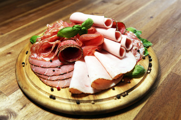 Food tray with delicious salami, pieces of sliced ham, sausages,salad and vegetable. Meat platter with selection